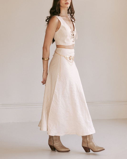 Woman wearing a white dress with a belt and boots against a plain background
